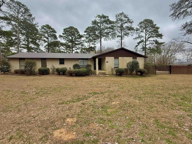 view of front facade with a front yard, brick siding, fence, and a chimney