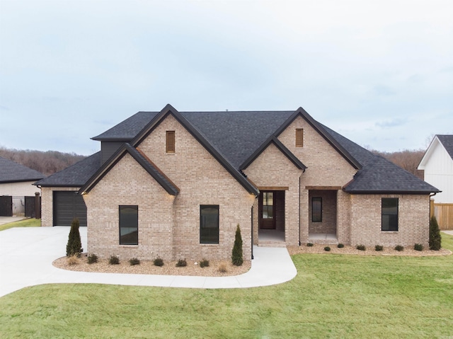 french country inspired facade featuring driveway, roof with shingles, a front yard, and brick siding