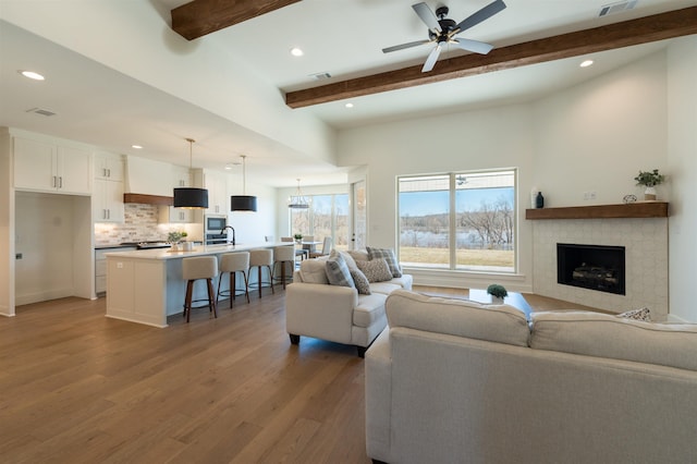 living area featuring ceiling fan, recessed lighting, dark wood-type flooring, visible vents, and beam ceiling