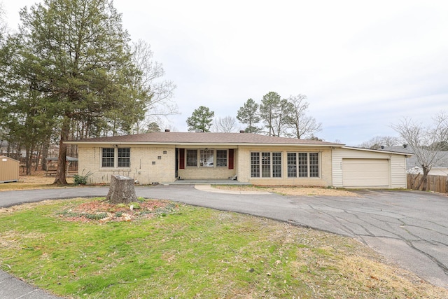 single story home with an attached garage, driveway, brick siding, and a front yard