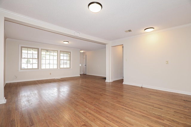 unfurnished room with ornamental molding, visible vents, baseboards, and wood finished floors