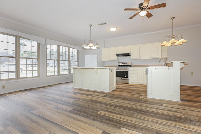 kitchen featuring stainless steel range, visible vents, hanging light fixtures, light countertops, and under cabinet range hood