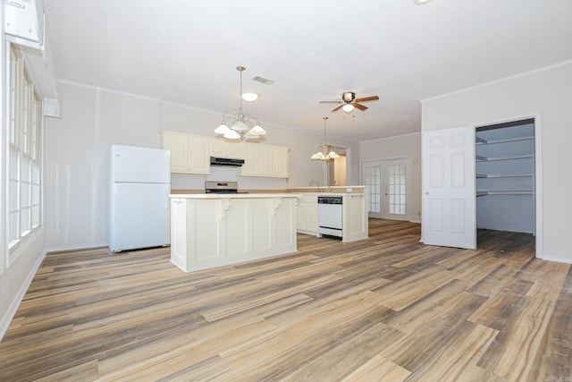 kitchen with white appliances, white cabinets, hanging light fixtures, light countertops, and under cabinet range hood