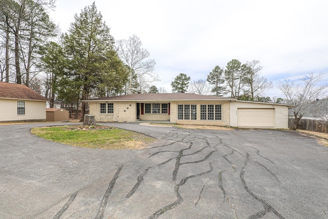 single story home with aphalt driveway, brick siding, and an attached garage