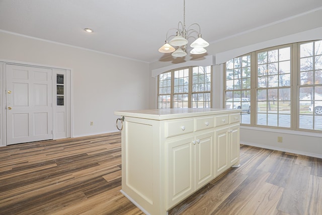 kitchen with crown molding, pendant lighting, light countertops, and a kitchen island