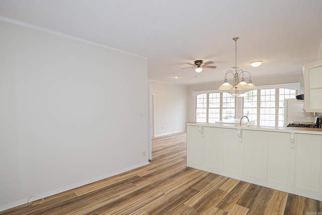 kitchen with crown molding, light countertops, freestanding refrigerator, white cabinetry, and wood finished floors