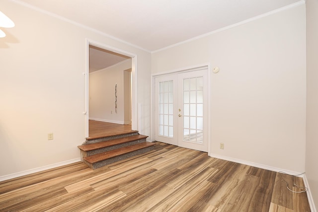 empty room featuring ornamental molding, french doors, wood finished floors, and baseboards