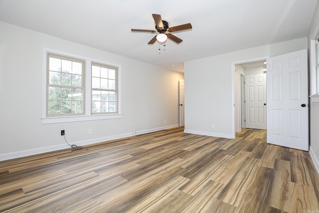 spare room featuring baseboards, dark wood finished floors, and a ceiling fan