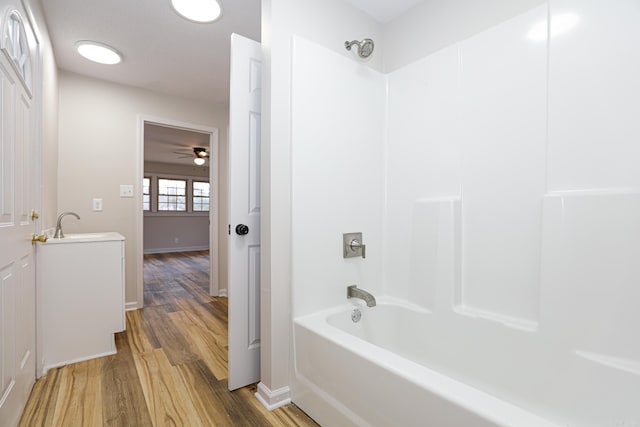 full bathroom featuring a sink, baseboards, shower / washtub combination, and wood finished floors