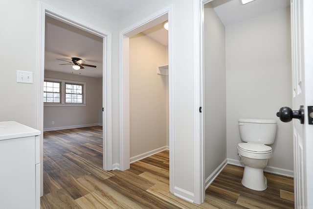 bathroom featuring baseboards, toilet, ceiling fan, wood finished floors, and vanity