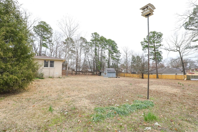 view of yard featuring fence, an outdoor structure, and a storage unit