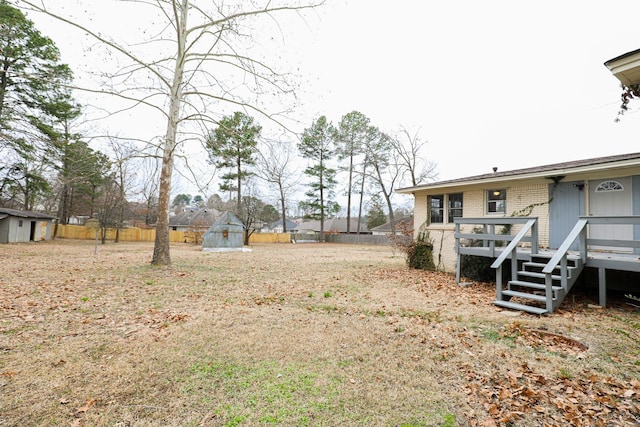 view of yard featuring a fenced backyard, stairs, a deck, and an outbuilding