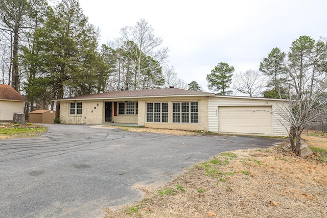 ranch-style home featuring an attached garage, aphalt driveway, and brick siding