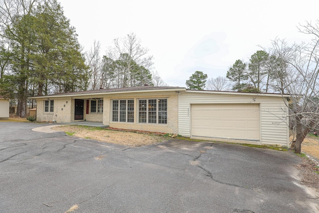 ranch-style home with brick siding, an attached garage, and aphalt driveway