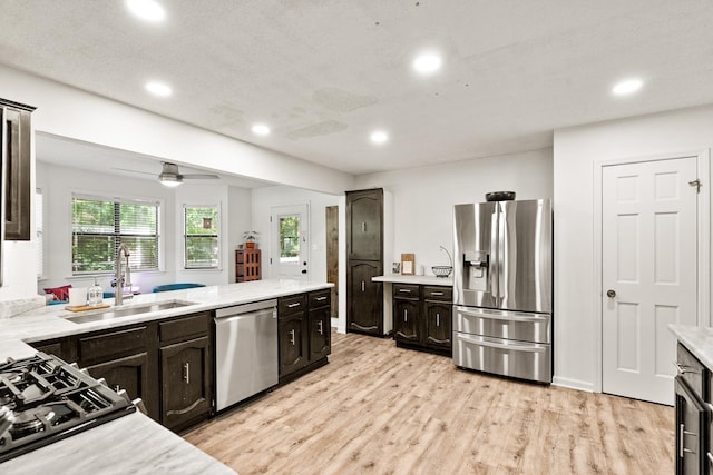 kitchen featuring recessed lighting, light countertops, appliances with stainless steel finishes, a sink, and light wood-type flooring