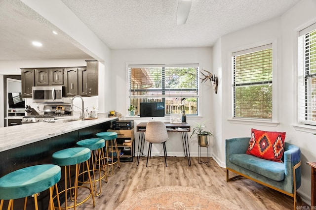 interior space with a breakfast bar, light countertops, stainless steel microwave, dark brown cabinets, and range