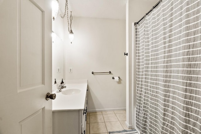 full bath with a textured ceiling, tile patterned flooring, vanity, and baseboards