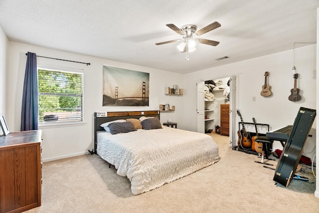 bedroom featuring ceiling fan, visible vents, a textured ceiling, and light colored carpet