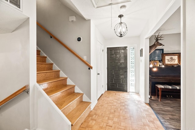 entryway featuring parquet flooring, baseboards, visible vents, and a textured ceiling