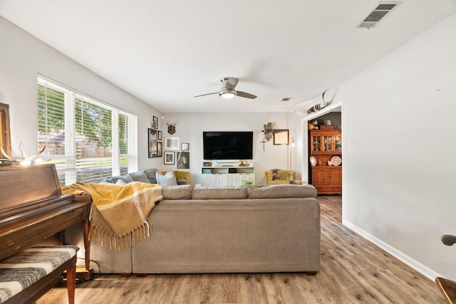 living area with a ceiling fan, baseboards, visible vents, and wood finished floors