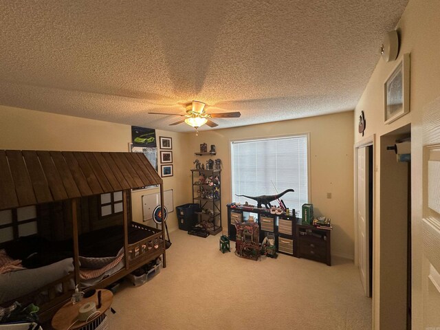 bedroom with ceiling fan, carpet, and a textured ceiling