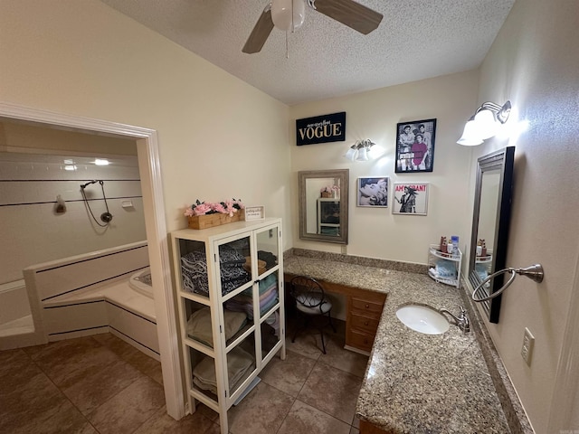 tiled bedroom featuring a textured ceiling, ceiling fan, built in desk, and a sink