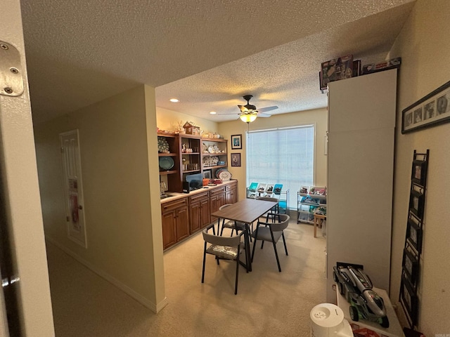 dining area with a textured ceiling, recessed lighting, baseboards, light colored carpet, and ceiling fan