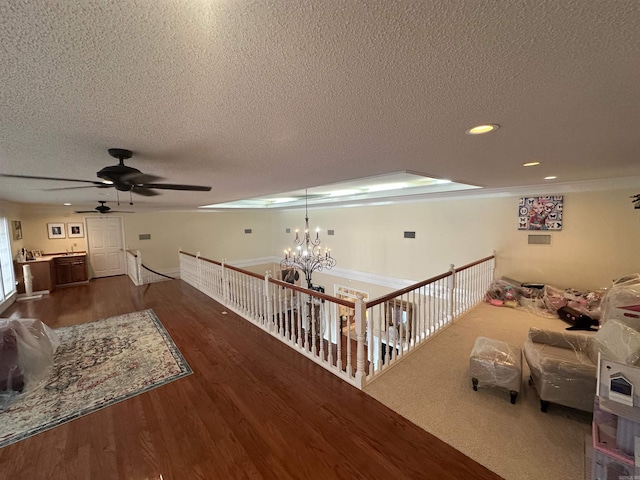 corridor with an upstairs landing, a textured ceiling, dark wood finished floors, recessed lighting, and a chandelier