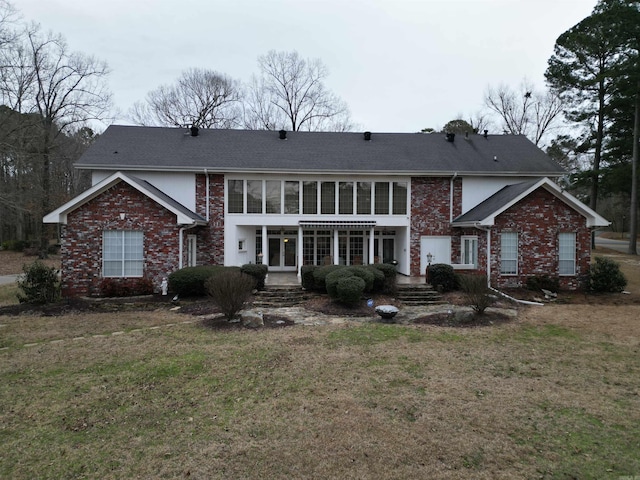 rear view of property featuring french doors, brick siding, and a lawn