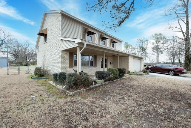 view of front facade with brick siding, covered porch, an attached garage, fence, and driveway