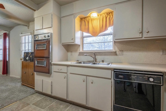 kitchen with white cabinets, black dishwasher, light countertops, and a sink