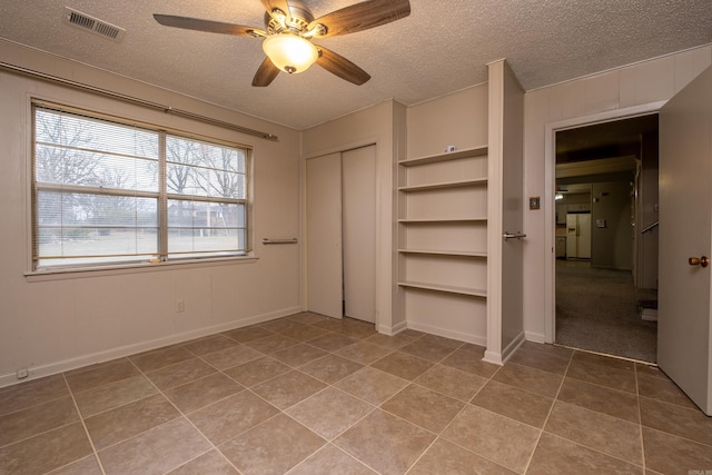 unfurnished bedroom featuring a ceiling fan, a closet, visible vents, and a textured ceiling