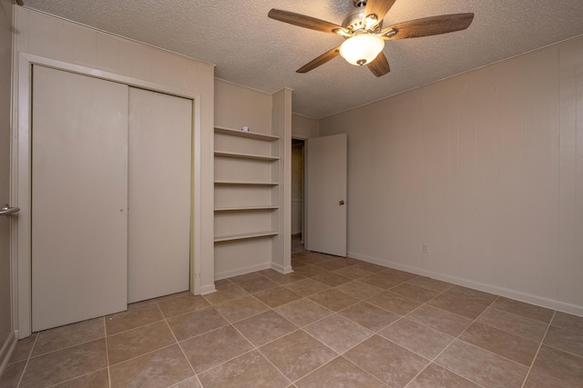 unfurnished bedroom featuring a ceiling fan, a closet, light tile patterned flooring, and a textured ceiling