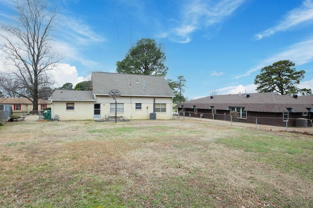 rear view of property featuring a fenced backyard, central AC, and a yard