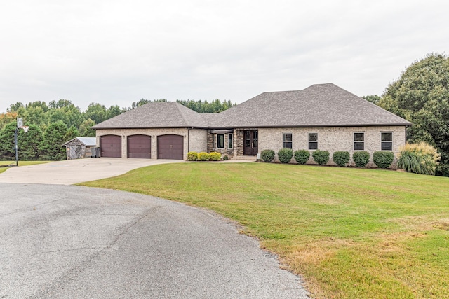 view of front facade with a garage, driveway, a shingled roof, and a front yard