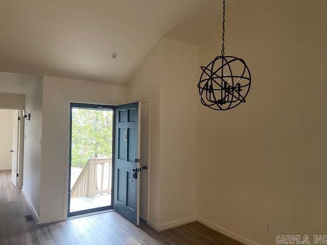 foyer entrance featuring vaulted ceiling, baseboards, and wood finished floors