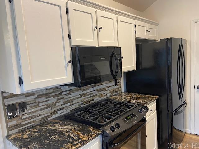 kitchen featuring dark stone countertops, white cabinetry, backsplash, and black appliances