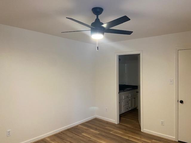 interior space with dark wood-style floors, ceiling fan, and baseboards