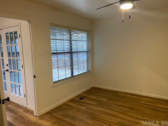 unfurnished room featuring wood finished floors, visible vents, a ceiling fan, baseboards, and french doors