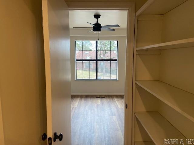 doorway featuring ceiling fan, baseboards, and wood finished floors