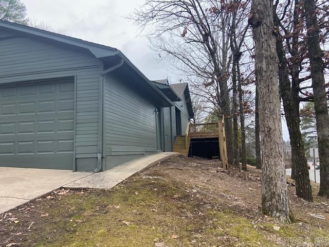 view of property exterior featuring concrete driveway, a deck, and an attached garage