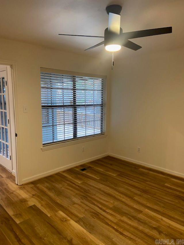 empty room with baseboards, a ceiling fan, and wood finished floors