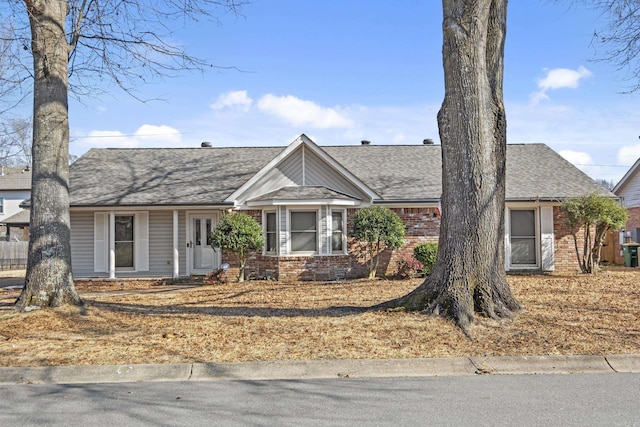 single story home featuring a shingled roof and brick siding