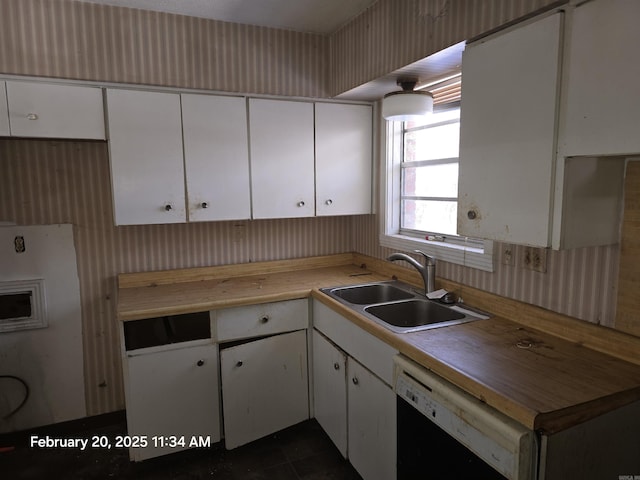 kitchen featuring black dishwasher, butcher block counters, a sink, and white cabinets