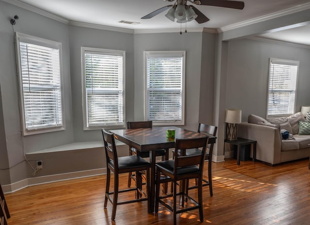 dining area with baseboards, wood finished floors, visible vents, and crown molding