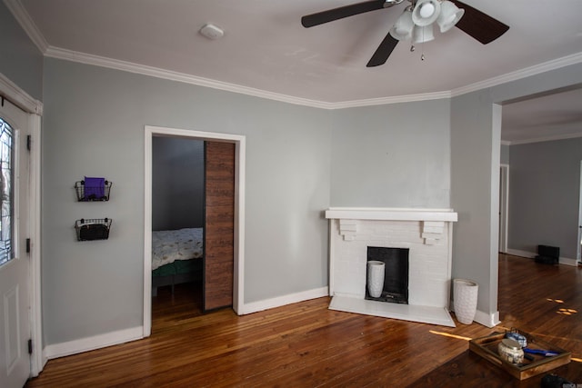 unfurnished living room with ornamental molding, dark wood-style flooring, a brick fireplace, and baseboards