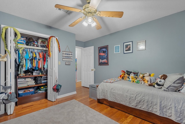 bedroom featuring baseboards, visible vents, a ceiling fan, light wood-type flooring, and a closet