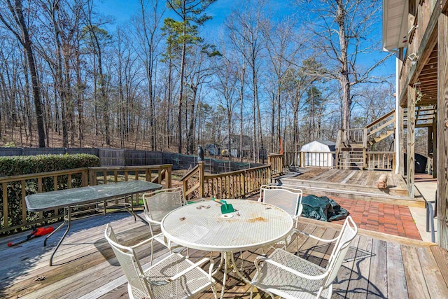 wooden deck featuring stairs, outdoor dining area, and fence