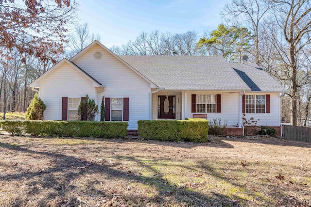 ranch-style home featuring roof with shingles, a front yard, and fence