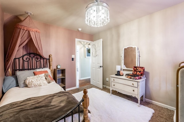 carpeted bedroom featuring baseboards and an inviting chandelier